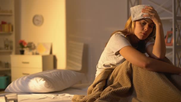 Kranke Dame mit Handtuch auf der Stirn, die an Migräne leidet, zu Hause im Bett liegend — Stockvideo