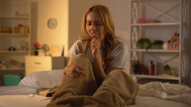 Depressieve vrouw kauwen donut zittend op bed, stress overeten, ongezond eten — Stockvideo