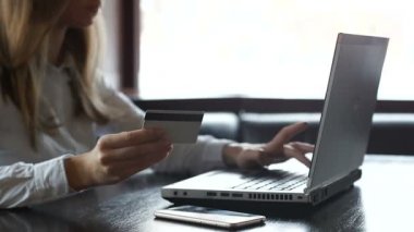 Bayan kredi kartı tutan ve dizüstü bilgisayarda yazma, web mağazasında online alışveriş