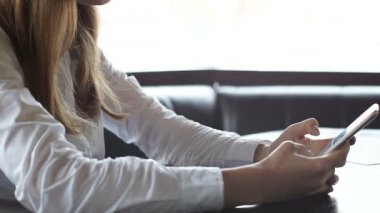 Genç bayan akıllı telefondaki fotoğrafları kaydırıyor ve gülümsüyor, zevk anıları