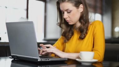 Kadın blogger kafede dizüstü bilgisayar üzerinde çalışıyor, sosyal ağda yayın gönderme