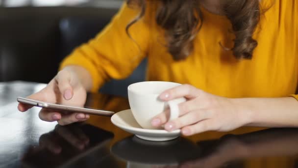 Mujer tomando café en la cafetería y usando smartphone, charlando en las redes sociales — Vídeos de Stock