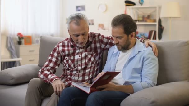 Vater und Sohn sehen alte Fotos und teilen gute Erinnerungen Familientradition — Stockvideo