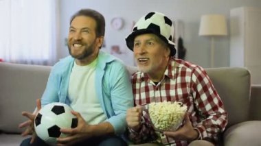 Heyecanlı baba ve oğlu favori futbol takımı için tezahürat, tv oyunu izlerken
