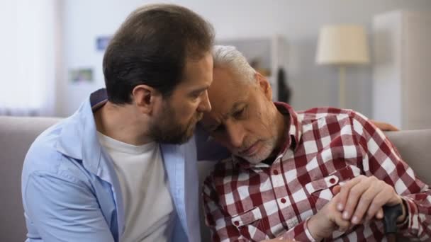 Junger Mann umarmt und spricht mit depressivem alten Vater, leidet unter Tod seiner Frau, Verlust — Stockvideo