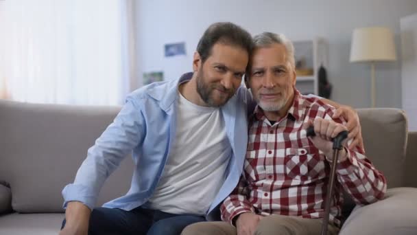 Счастливые улыбающиеся отец и сын смотрят в камеру, социальное страхование, статистика — стоковое видео