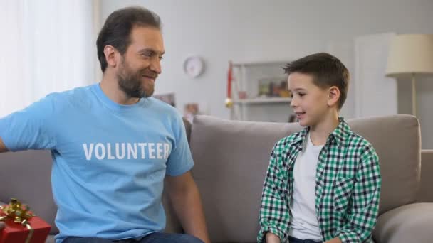Giovane volontario dando regalo di compleanno ragazzo, adattamento sociale per orfani, cura — Video Stock
