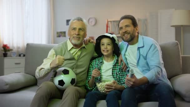 Aufgeregter Opa, Vater und Sohn freuen sich über den Sieg der Fußballnationalmannschaft bei einem Heimspiel — Stockvideo