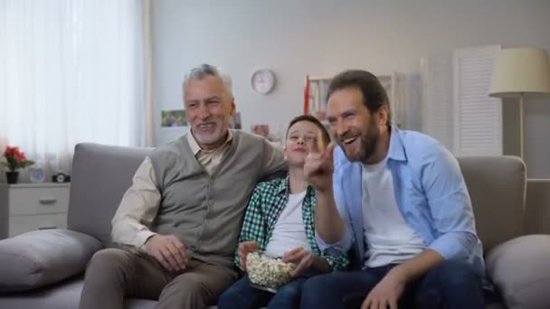 Gioioso nonno, padre e figlio godendo spettacolo comico in TV, divertirsi insieme — Video Stock