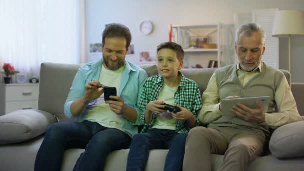 Взрослые мужчины прокручивают гаджеты, мальчик-подросток играет в видеоигры, гаджет наркомании — стоковое видео