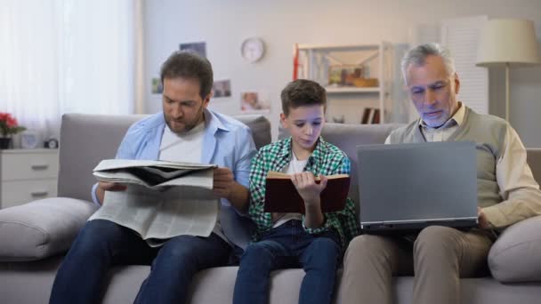 Vader en zoon lezen boek en krant, veroudering man houden laptop, generaties — Stockvideo