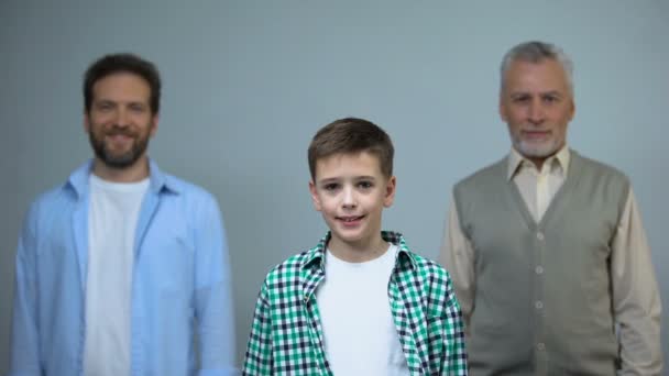 Young boy looking at camera, middle-aged and senior men on background, support — Stock Video