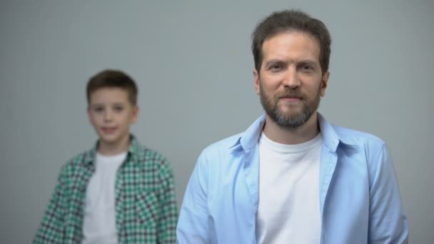 Hombre de mediana edad sonriendo a la cámara niño de pie detrás, recuerdos de la infancia — Vídeos de Stock