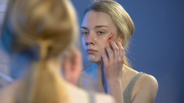 Sad female victim looking at face wound in mirror, domestic violence, abuse — Stock Video