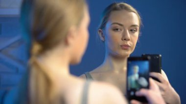 Genç bayan aynanın önünde selfie için poz veriyor, sosyal ağlar bağımlılığı, eğlence