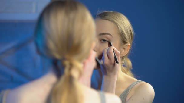Mulher muito adolescente aplicando eyeliner frente do espelho, aprendendo a fazer maquiagem — Vídeo de Stock