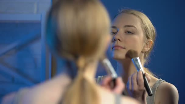 笑顔の若い女性がフェイスパウダーを塗り、鏡でキスジェスチャーをする — ストック動画