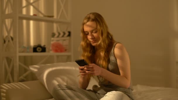 Glücklicher Teenager, der zu Hause mit dem Smartphone chattet, Kommunikation mit dem Freund — Stockvideo