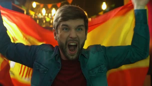 Szakállas sportrajongó hullámzó spanyol zászló pub, örvendezve a nemzeti csapat győzelme — Stock videók