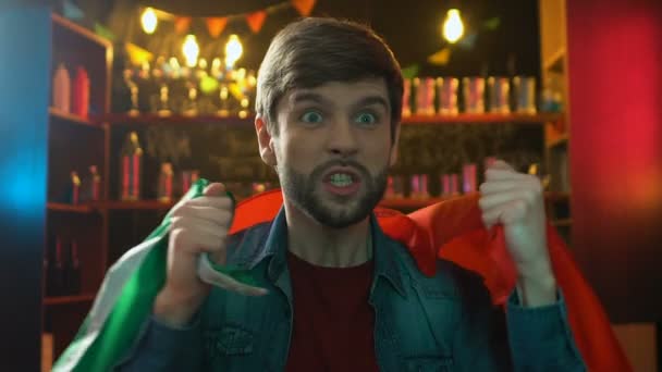 Nervous sports fan with Portuguese flag watching match in pub upset about defeat — Stock Video