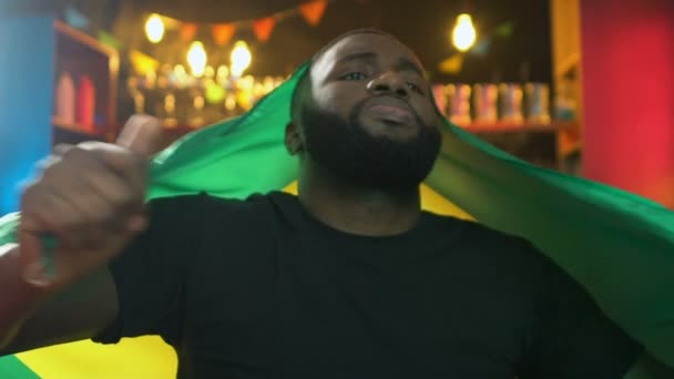 Afro-american sports fan with Brazil flag displeased about favorite team losing — Stock Video