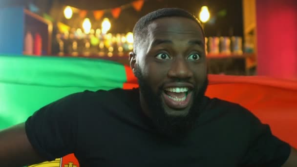 Izgatott fekete rajongó integetett portugál zászló, örvendezve a nemzeti sport csapat győzelme — Stock videók