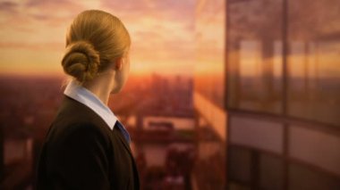 Genç iş çalışanı gün batımına bakıyor, başarılı bir iş kariyeri hayal ediyor