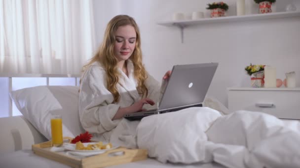 Красивая девушка заканчивает работу на ноутбуке, чтобы съесть сладкий десерт, сахар для мозга — стоковое видео