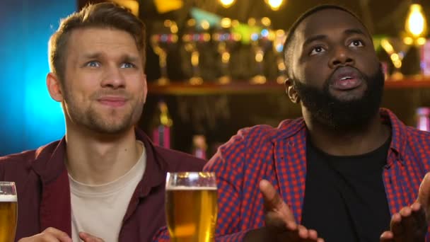 Amigos multiétnicos assistindo jogo esportivo no pub, torcendo por diferentes equipes — Vídeo de Stock
