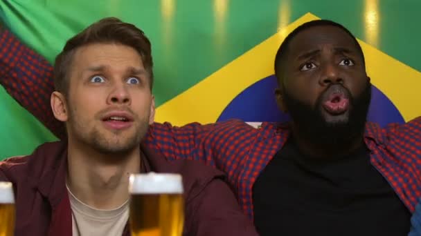 Болельщики в баре держат бразильский флаг, расстроены потерей сборной — стоковое видео