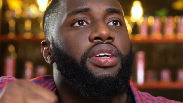Hombre afro-americano molesto por pérdida de equipo deportivo favorito, viendo el partido en el pub — Vídeos de Stock