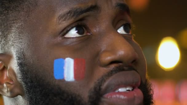Чорний чоловічий вентилятор з французьким прапором на щоці засмутився про втрату національної команди, спорт — стокове відео