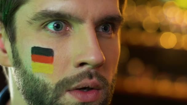 Männlicher Fan mit Deutschland-Fahne auf der Wange ärgert sich über das verlorene Spiel seiner Lieblingsmannschaft — Stockvideo