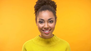 Pozitif kız öğrenci sarı arka plan, doğal güzellikleri kamera bakıyor