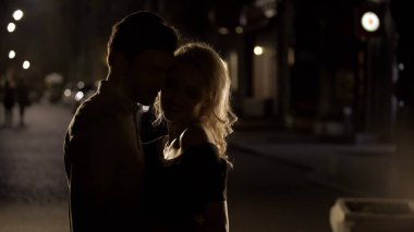 Sarışın kadın alay ve gece sokak, siluetleri erkek sarılma