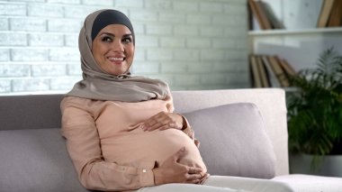 Karın hafifçe dokunma, ev, Doğum öncesi bakım dinlenme hijab mutlu hamile kadın
