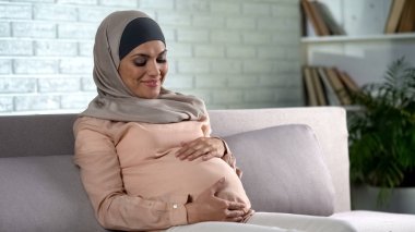 Başörtüsü tutarak karın, bebek beklentisi, annelik gülümseyen hamile bayan