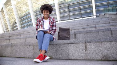 Açık havada ödev, kameraya gülümseyen güzel Afro-Amerikan kız öğrenci