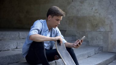 Patenci çocuk merdivenlerde oturan ve akıllı telefon kaydırma, spor ekipmanları sipariş