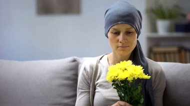 Woman with cancer holding bouquet of beautiful flowers and enjoying life clipart