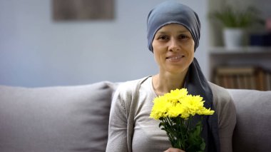 Kanser hastası bir kadın çiçek kokluyor ve hayattan zevk alıyor. Güzel bir hediye.