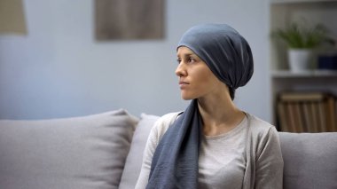 Onkoloji hastanesinde kanepede oturan başörtülü üzgün genç bayan