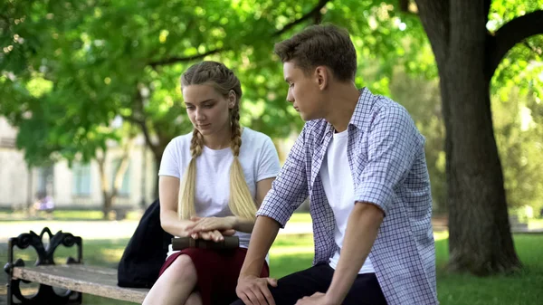 Indifferent teens sitting on bench, bad blind date, wasting time, ignoring