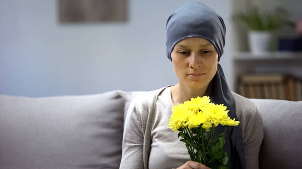 Woman with cancer holding bouquet of beautiful flowers and enjoying life