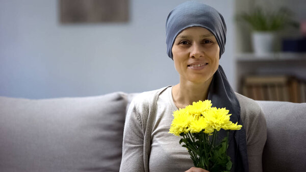 Woman with cancer remission smelling flowers and enjoying life, beautiful gift