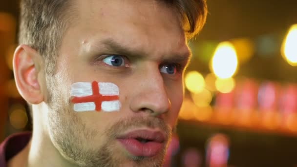 English football fan with flag on cheek upset about favorite team losing match — Stock Video