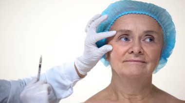 Yaşlı kadın güzellik kliniğinde yüz anti-aging kırışıklık dolgu alma, kozmetoloji