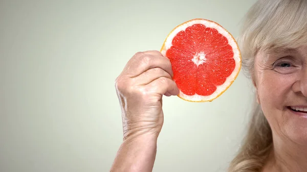 Счастливая Улыбающаяся Пожилая Женщина Показывающая Кусочек Сочного Грейпфрута Полулицо Крупным — стоковое фото
