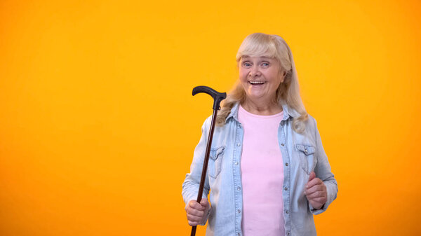 Smiling aged lady holding walking stick, equipment for disabled or elderly