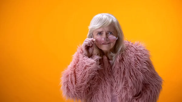 Aging positive lady taking off glasses, looking directly at camera, scrutinizing